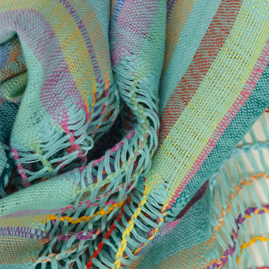 Lattice Weave Scarf in Aqua, made from multicolor cotton threads with aqua overtones, with fringe. The scarf is laid flat, wrapped with a circle on white background.