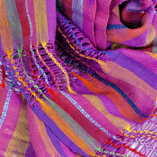 Lattice Weave Scarf in Purple, made from multicolor cotton threads with purple overtones, with fringe. The scarf is laid flat, wrapped with a circle on white background.